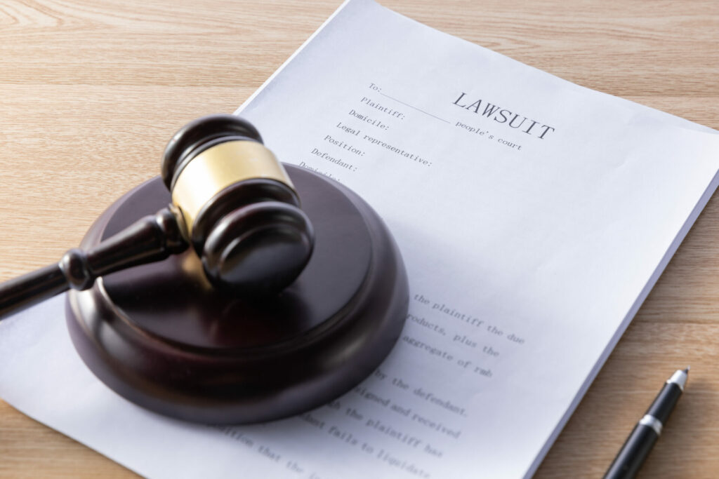 Wooden gavel with lawsuit paperwork on a wooden desktop