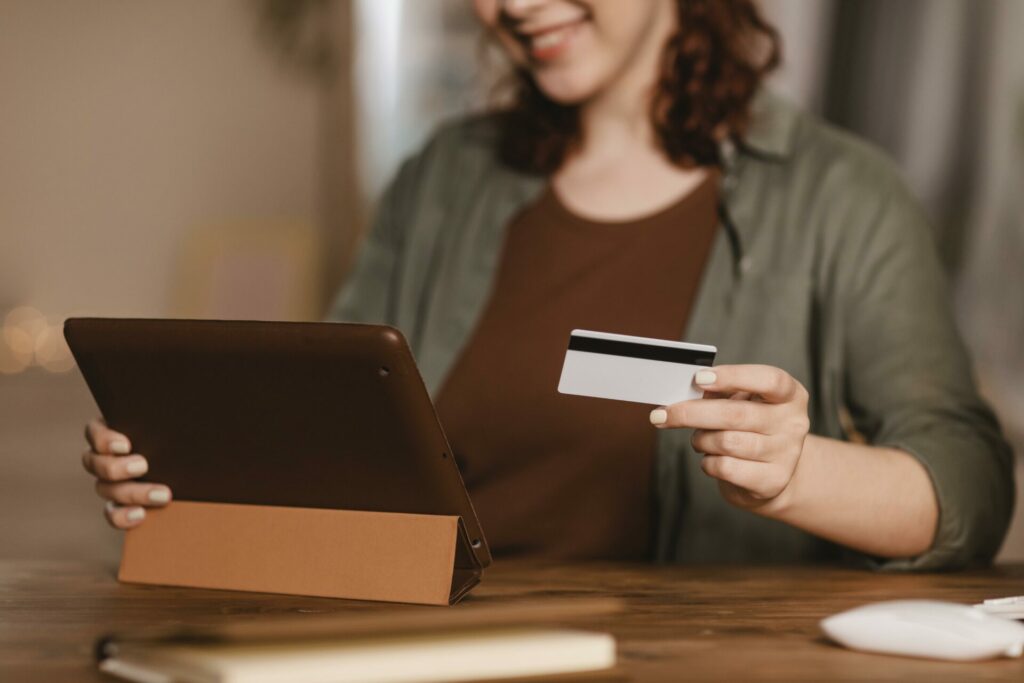 Smiling woman holding a tablet and a credit card, potentially making an online purchase.